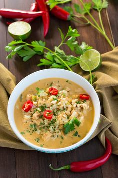 a white bowl filled with soup and garnished with cilantro, red peppers