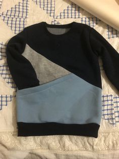 a blue and grey sweater laying on top of a bed