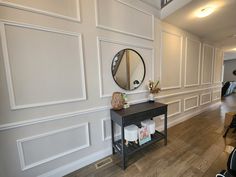 a room with white walls and wood flooring has a mirror on the wall next to it