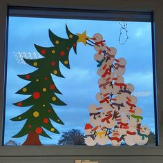 a christmas tree made out of cut outs in front of a window with blue sky and clouds