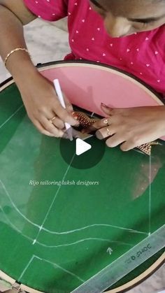 a woman sitting at a table cutting paper with scissors