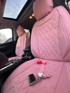 the interior of a car with pink leather seats and electronic gadgets on the floor