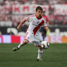 a man kicking a soccer ball on top of a field