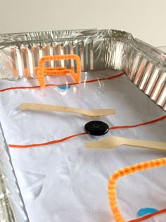 an ice hockey rink made out of aluminum foil with popsicle sticks sticking out of it