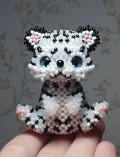 a hand holding a small white and black beaded dog