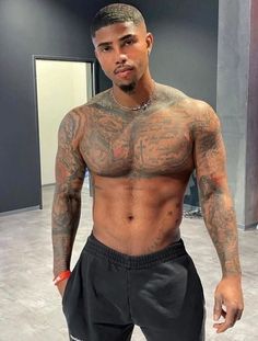 a man with tattoos on his chest and no shirt standing in front of a mirror