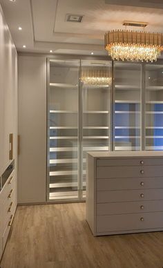 an empty room with a chandelier hanging from the ceiling and cabinets in front of it