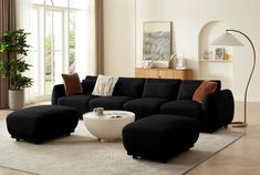 a living room with black couches and white coffee table in front of large windows