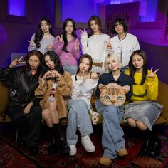 a group of young women sitting next to each other in front of a purple background