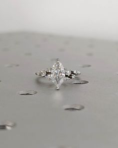 a diamond ring sitting on top of a silver surface with drops of water around it