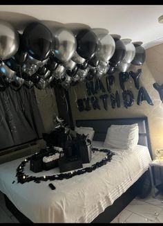 a bedroom decorated for a birthday with black and silver balloons