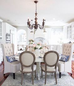 a dining room table with four chairs and a chandelier hanging from the ceiling