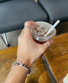 a person is holding a drink with a straw in their hand while sitting at a table