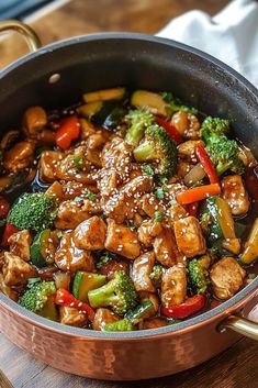 a pan filled with chicken and broccoli on top of a wooden table