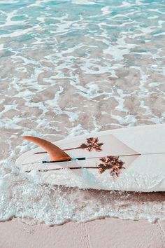 the surfboard is laying on its side in the water at the edge of the beach