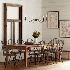 a dining room table with chairs and a vase filled with flowers on top of it