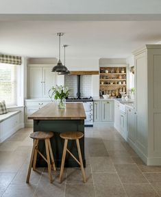 a kitchen with two stools in front of an island