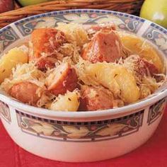 a bowl filled with pasta and meat on top of a table next to some apples