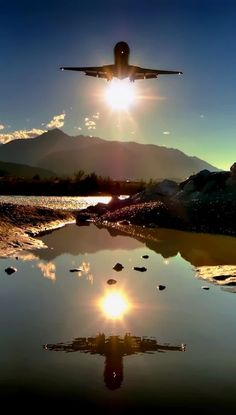 an airplane is flying low over the water at sunset with mountains in the back ground