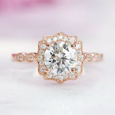 Glittering diamonds and light-catching milgrain form an ornate halo around the center gem in this breathtaking vintage-inspired ring. ►Available in 14K solid rose gold. This ring can be also custom made in white or yellow gold. Metal can be upgraded to 18K at additional cost. ►Matching band can be custom made to order. ►Average band width: 2.2 mm ►Halo size: 10.5mm (approx.) ►Gemstone information: Moissanite ring option: Moissanite center & accent stones Shape: Round, Brilliant Color: D Clarity: Elegant Gia Certified Rose Gold Diamond Ring, Gia Certified Rose Gold Wedding Diamond Ring, Vintage Halo Diamond Wedding Ring, Vintage Wedding Diamond Ring With Halo, Heirloom Style Rose Gold Cluster Ring, Gia Certified Rose Gold Wedding Ring, Elegant Gia Certified Cluster Ring For Wedding, Elegant Gia Certified Cluster Wedding Ring, Gia Certified Rose Gold Jewelry For Wedding