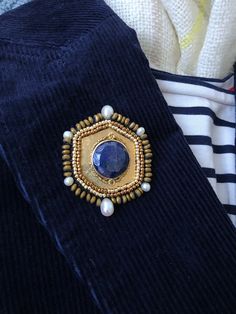 "A handsome and eye catching hexagon brooch with a beautiful lapis stone center.  Hand sawed and hammered, then adorned with a lapis and brass bead bezel. Hematite and pearls add the eye catching border. Backed with green velvet this brooch is a great versatile accent day or night whether affixed to a blazer, jacket, scarf or clutch. This is the only one available. Size Details: Slight variations in texture and size may occur due to the handmade nature of my work. - Hexagon: 2-3/8\" L x 1-3/4\"W Lapis Stone, Brooch Handmade, Cameo Brooch, Pearl Brooch, Brooches Handmade, Silk Thread, Green Velvet, Jewelry Art, Handmade Natural