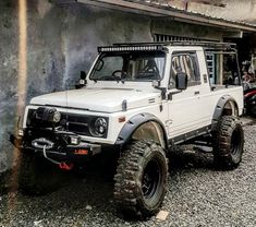 a white truck parked in front of a building with rocks and gravel on the ground