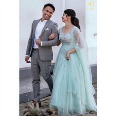 a man and woman dressed in formal wear standing next to each other on the sidewalk