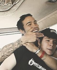 two young men are smiling and having fun in the back seat of a car while another man is brushing his hair