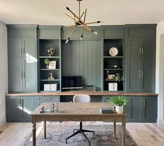 a kitchen with green cabinets and a wooden table in the center, surrounded by an area rug