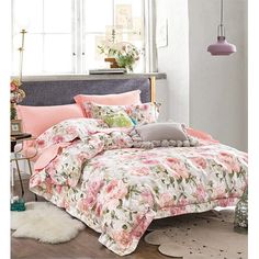 a bed with pink and white flowers on it in a room next to a window