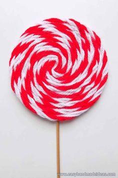 a red and white lollipop sitting on top of a wooden stick