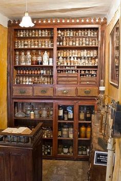 an old fashioned pharmacy cabinet with lots of jars on the shelves and drawers in it