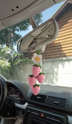 the interior of a car is decorated with pink strawberries and flowers hanging from the dash board