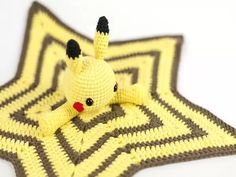 a crocheted stuffed animal laying on top of a star shaped rug in yellow and brown