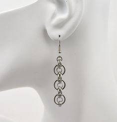 With its sleek curves, these earrings are modern and versatile. Multiple stainless steel ring sizes are used to create a ring-within-a-ring pattern. Earrings are approximately 2.5" long from top of earwire. Stainless Steel Wire Jewelry, Piercing Reference, Chain Mail Earrings, Egyptian Inspired Jewelry, Chainmaille Jewelry Patterns, Chainmaille Jewelry, Ring Pattern, Glow Stars, Earring Hoop