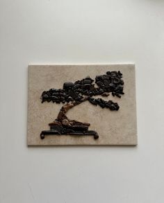 a piece of art that looks like a tree with rocks on it and a person sitting in the background