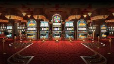 a casino room filled with lots of slot machines and red carpeted stairs leading up to them