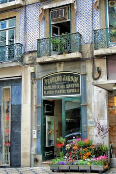 an old building with flowers in front of it and balconies on the second floor