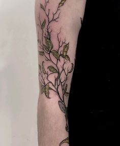 a person with a tattoo on their arm has a branch and scissors in the foreground