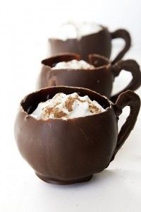 three chocolate cups filled with marshmallows on top of a white countertop