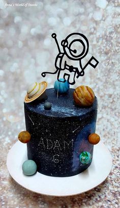 a black cake with planets on it sitting on a white plate next to a silver background