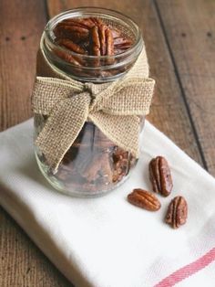 a glass jar filled with pecans sitting on top of a white napkin