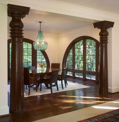 a dining room table and chairs with arched doorways in the center, surrounded by wood flooring