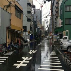 a city street with cars and bicycles parked on the side of it in the rain