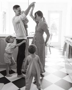 a black and white photo of a family in the kitchen