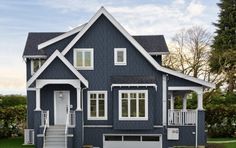 a blue house with white trim and windows on the second floor is next to green grass