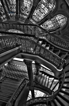 a spiral staircase with stained glass windows and wrought iron railings in black and white