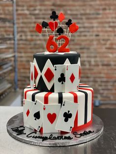 a three tiered cake decorated with playing cards and the number twenty eight on top