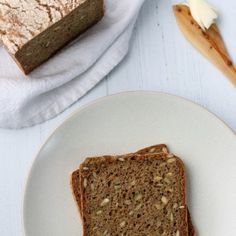 a piece of bread sitting on top of a white plate next to a loaf of bread