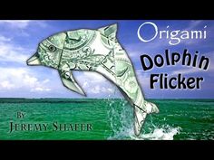 an origami dolphin is jumping out of the water with money bill in its mouth